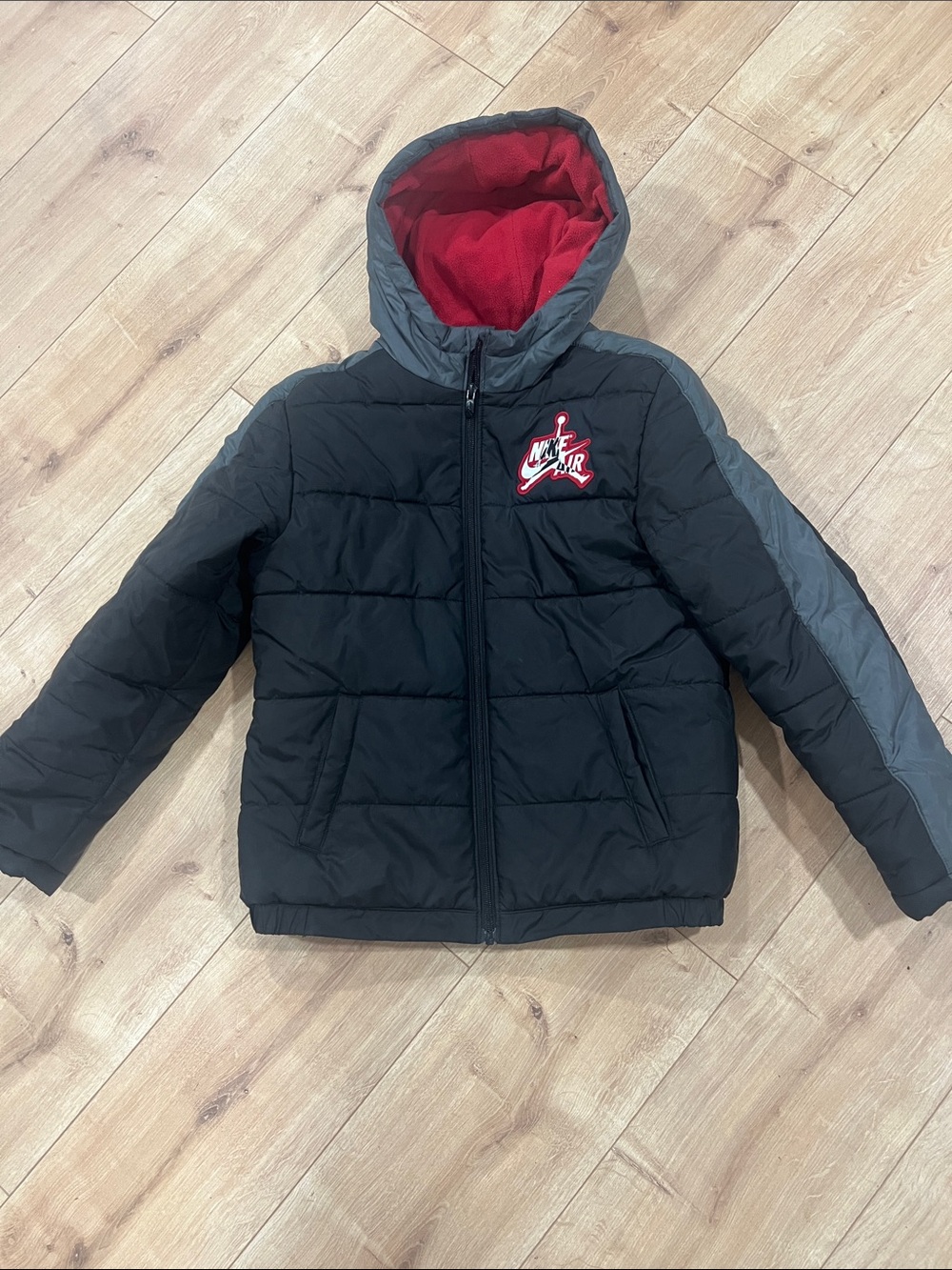 Nike Kids Black Puffer Jacket with Red Hood Lining and Gray Accents
